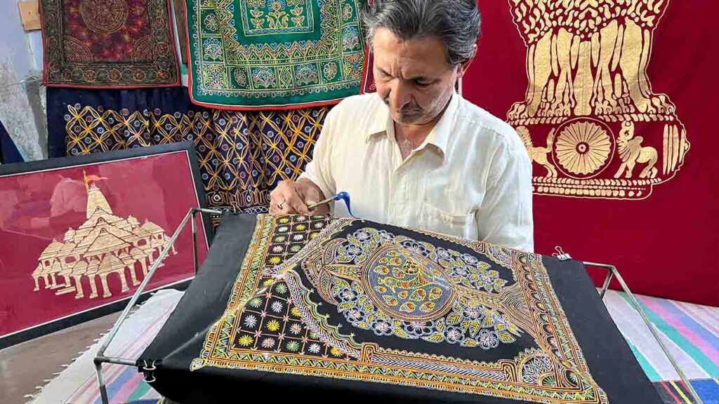 Madhapar studio interior displaying traditional Rogan tools — iron rod, wooden sticks, and jars of paint.
